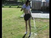 Cute Teen Waters The Grass And Gets Wet In The Process